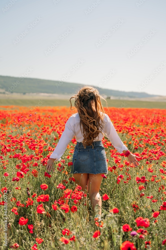 Woman poppies field. Back view of a happy woman with long hair in a poppy field and enjoying the beauty of nature in a warm summer day. Woman poppies field. Back view of a happy woman with long hair in a poppy field and enjoying the beauty of nature in a warm summer day.
