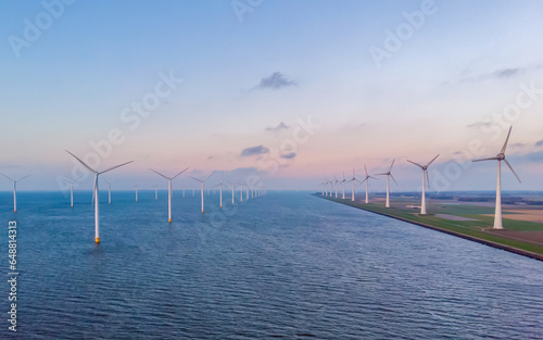 Fototapeta Naklejka Na Ścianę i Meble -  Sunset at Windmill Park in the ocean aerial view with wind turbine Flevoland Netherlands Ijsselmeer. Green Energy Production in the Netherlands
