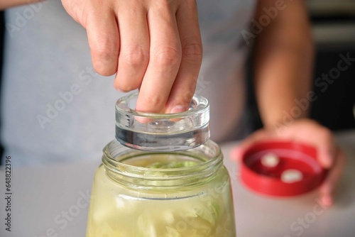 Foto Unrecognizable man putting the fermentation weight on the fermentation jar to prepare homemade sauerkraut or fermented cabbage