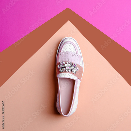 Trendy female white perforated leather loafer with light pink and brown details, decorated with rhinestones on a creative multicolor background. Fashion style and trend. Shoe sale marketing campaign.