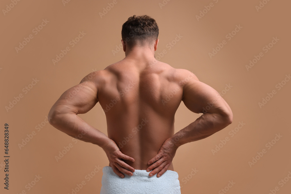 Fototapeta premium Man suffering from back pain on beige background, back view