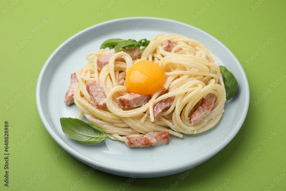 Delicious pasta Carbonara with egg yolk on light green background, closeup Delicious pasta Carbonara with egg yolk on light green background, closeup