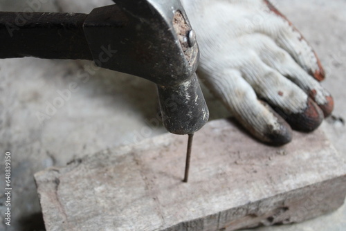 Closeup of nailing into a wooden board.Carpenter hands using hammer hit the nail on wood.