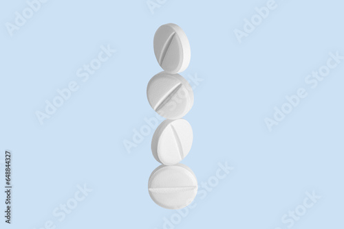 White capsules, pills and tablets flying up. On.blue background.