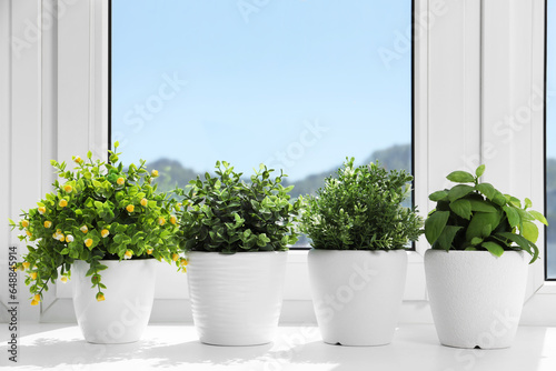 Artificial potted herbs on sunny day on windowsill indoors. Home decor