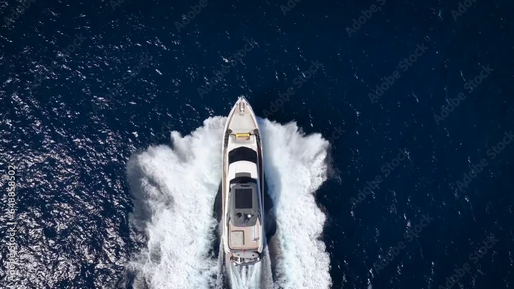 Aerial slow motion view of a luxury yacht cruising with high speed over blue ocean