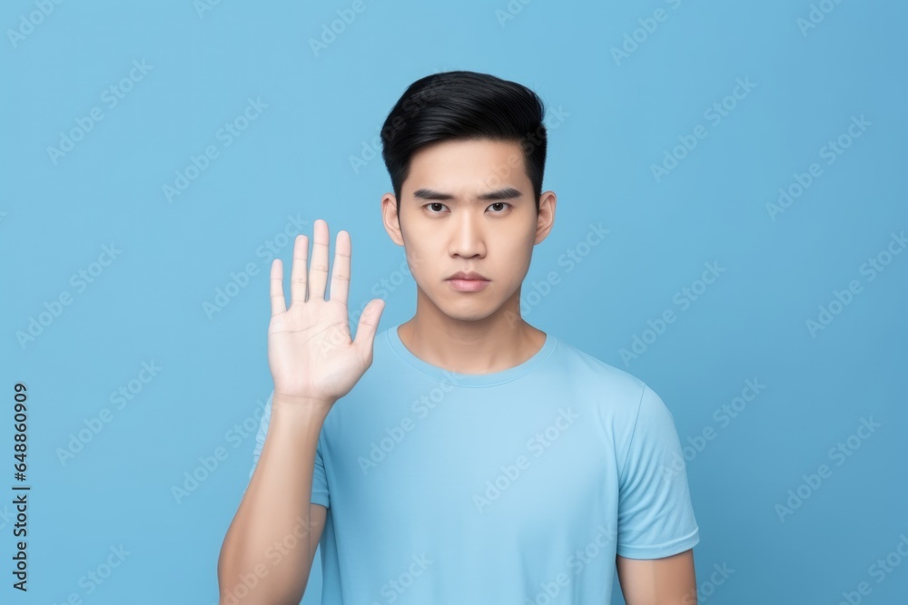 Portrait of young handsome Asian man showing STOP Portrait of young handsome Asian man showing STOP