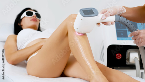 Obraz na płótnie Flash of diode laser hair removal, cosmetologist removes hair on beautiful female legs, hair removal for smooth skin, laser procedure in a beauty studio or clinic, body care hair removal