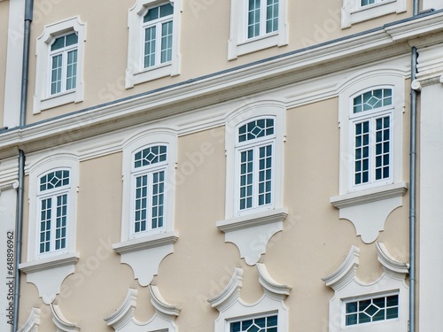 Elegant classical windows of white colour decorated with stucco ornaments on beige antique facades at daytime downtown Aveiro, Portugal. Portuguese vintage architecture