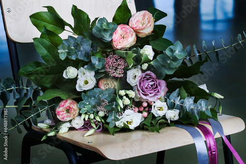 A beautiful bridal bouquet from a variety of exotic flowers and ribbons on a chair. Wedding bouquet made by a florist from a flower boutique on a chair. Bouquet of roses eucalyptus on Valentine day