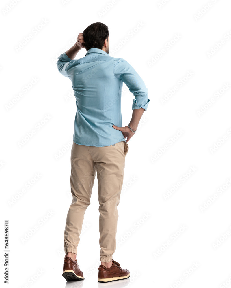 back view of confused young man scratching head and thinking back view of confused young man scratching head and thinking