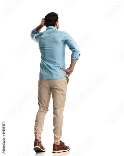 back view of confused young man scratching head and thinking