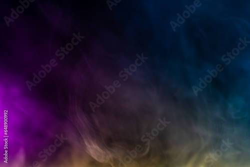 Blurred photo texture of colored smoke on a black background.