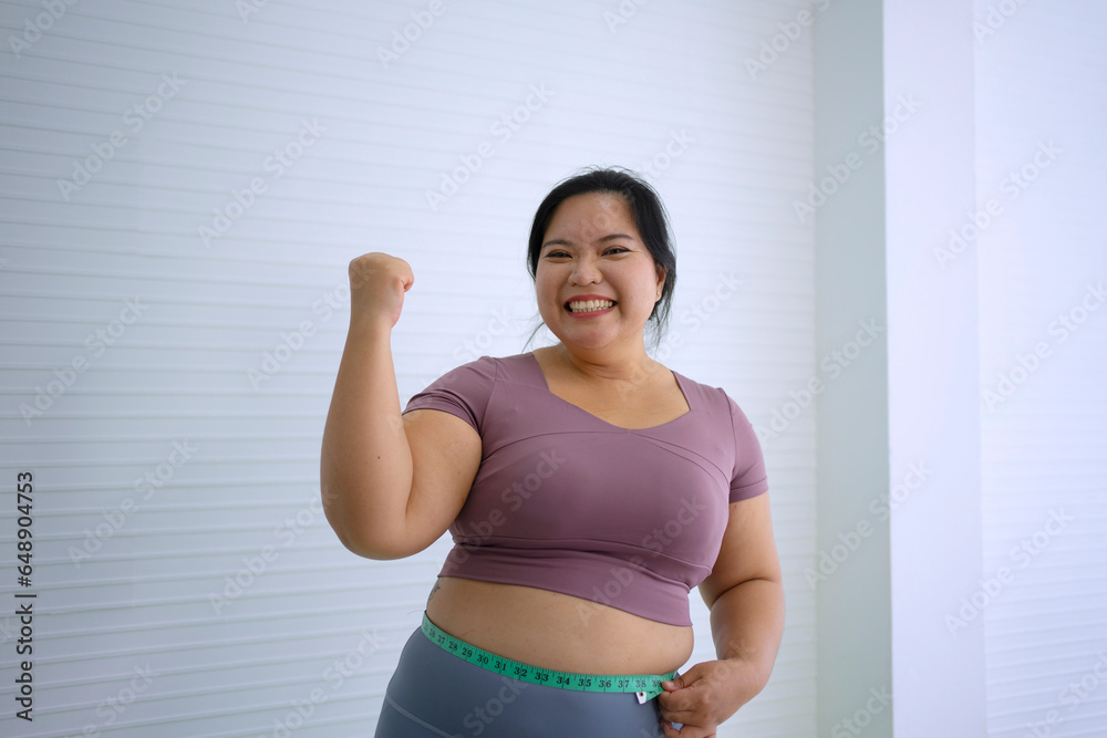 Plus size woman is measure her waist after exercise.