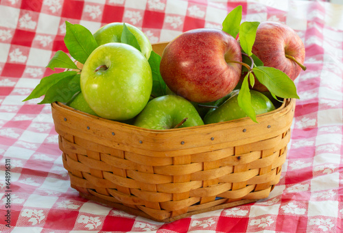 Apples in a wicker basket on the checkerboard table cloth