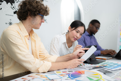 Multiethnic team of architects and designers are meeting to brainstorm design an application smartphone on a bright modern office working on a laptop.