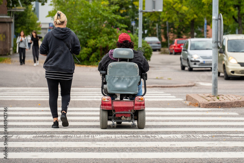 person in a electric wheelchair crossing a road with assistant