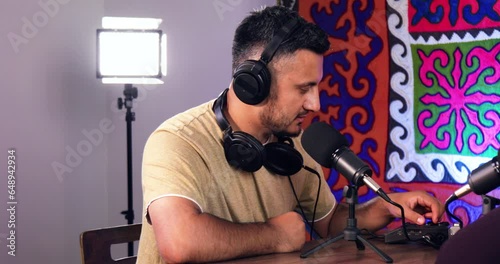 Bearded man adjusting multitrack podcast recorder equipment with headphones photo