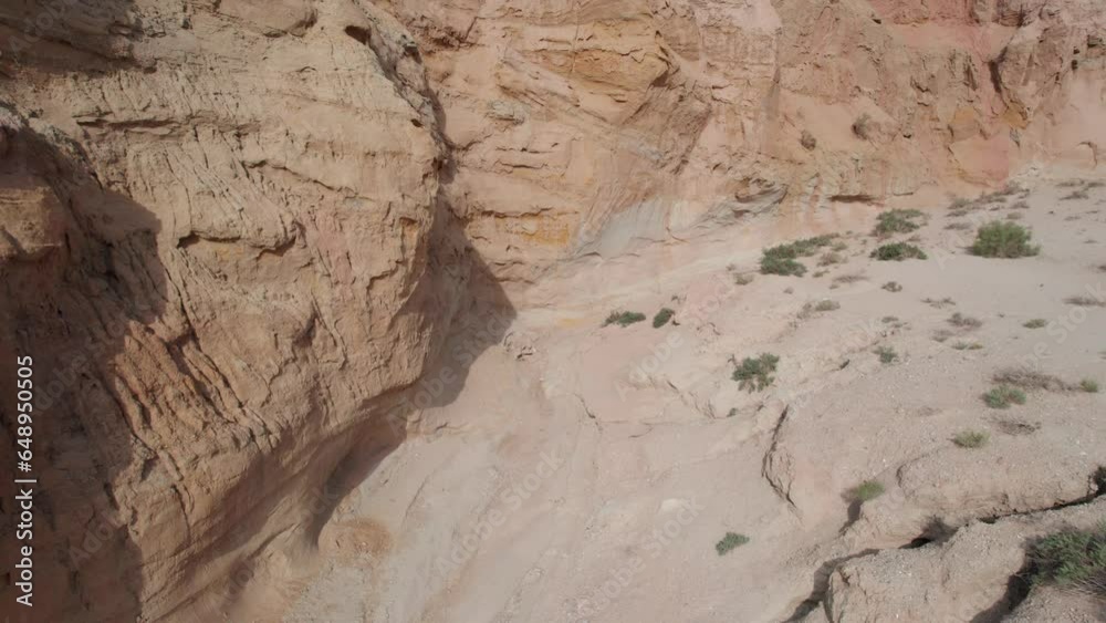 Colorful high mountains and a canyon made of clay. A large gorge with different rocks and different colors. Red, orange, white and yellow flowers of the walls of the rocks. A tourist walks. Aktau Colorful high mountains and a canyon made of clay. A large gorge with different rocks and different colors. Red, orange, white and yellow flowers of the walls of the rocks. A tourist walks. Aktau