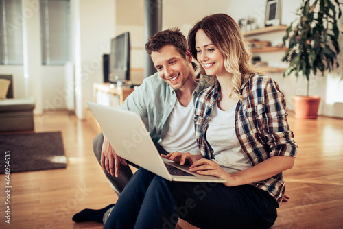Young Caucasian couple using a laptop in the living room at home photo