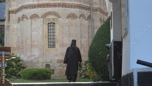 Rear view of black dressed nun walking to the monastery yard photo