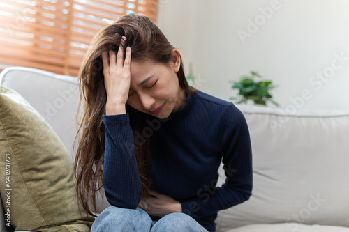 Foto Healthcare medical or daily life concept : Young lady suffer from stomachache or menstruation pain sitting on her sofa