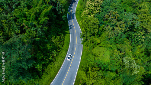 Aerial top view road in forest with car motion blur, Winding road through the forest. Car drive on the road between green forest. Ecosystem ecology healthy environment road trip..