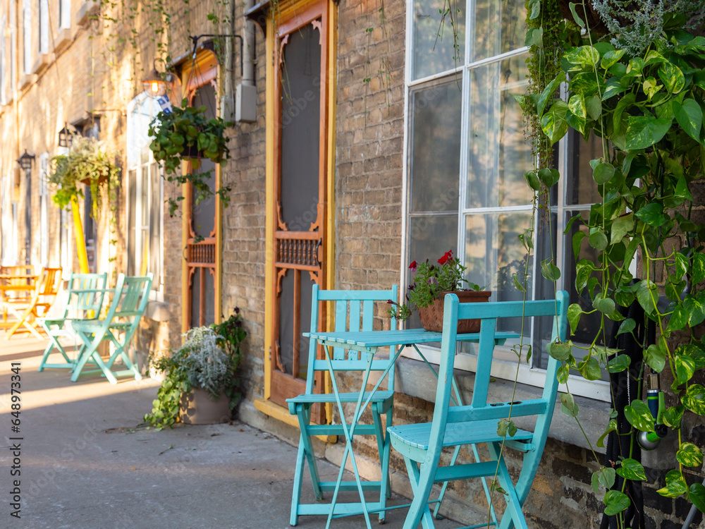 Horizontal side view of old brick house with bright turquoise bistro chairs and tables in the old town Champlain Street, Quebec City, Quebec, Canada