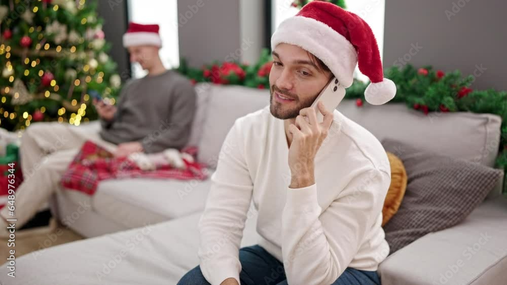 Two men couple celebrating christmas talking on smartphone at home Two men couple celebrating christmas talking on smartphone at home