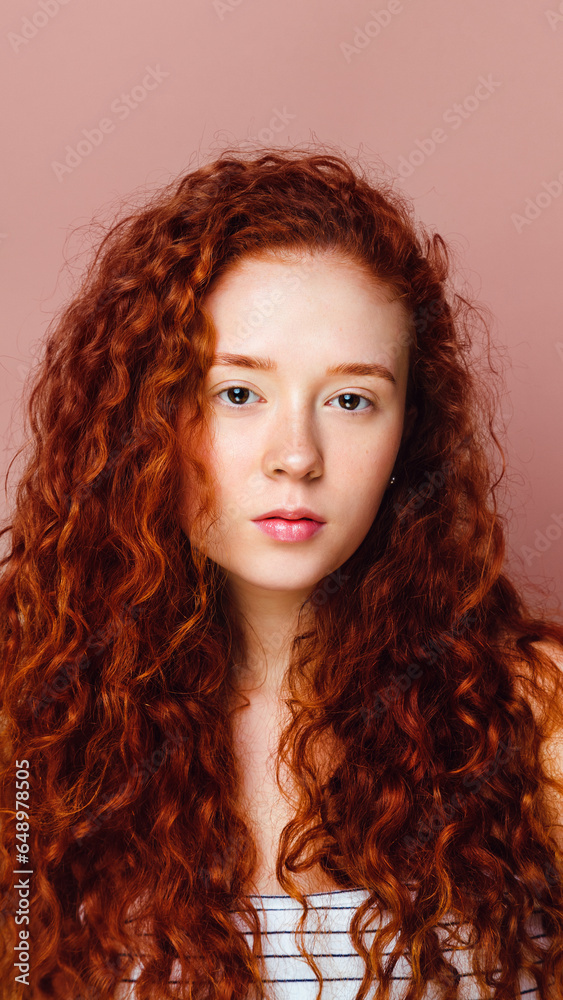 portrait of a cute curly girl on a pink background. Beautiful long red hair, no makeup portrait of a cute curly girl on a pink background. Beautiful long red hair, no makeup