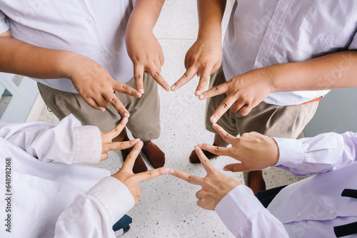 Asian students put their hands together in a fun gesture to get ready to complete the mission successfully.