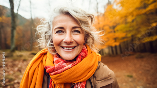 Fotografia Happy older woman smiles takes selfie autumn park