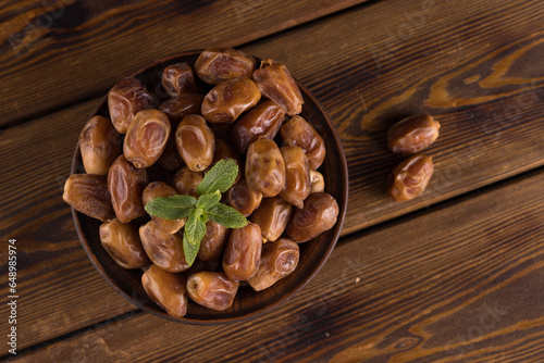 dates on a wooden table in a bowl. Overhead view