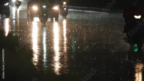大雨が降る夜の街を行き交う車とバイクと人々　台湾台北