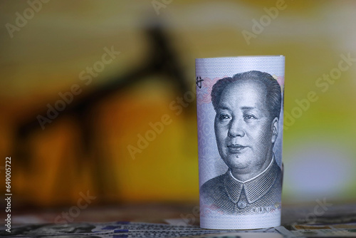Chinese yuan banknote on oil pump rig background. Concept of oil industry and prices photo