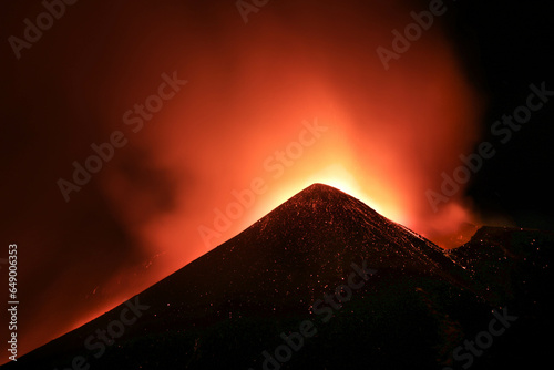 Cratere Etna in eruzione in primo piano durante suggestiva notte con lava incandescente ed emissione di cenere e fumo photo