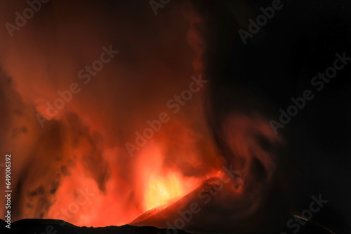 Etna panoramica suggestiva di notte sul vulcano in eruzione con lava tra cenere gas e vapore nel cielo notturno dal cratere del 13 Agosto 2023	 photo