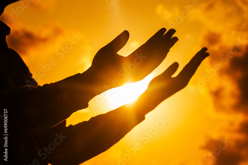 A captivating photograph showcasing the silhouette of a man, his figure rising against the radiant backdrop of the solstice sunset, as he offers his prayers.