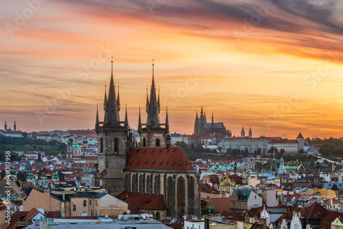 Prague cityscape of Church of Our Lady before Tyn and Prague castle in an orange twilight.