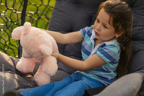 girl playing with her teddy bear being in nature