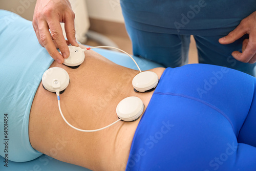Obraz na płótnie Male therapist maiking rehabilitational procedures with electrical stimulation