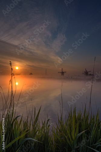 Foggy morning during the sunrise in the Munnikenpolder in Leiderdorp with the siloute of the windmills photo