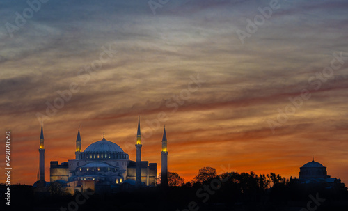 Pboto of mosque lit up after sunset on Istanbul skyline 