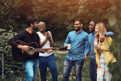 Fotografie A young man plays the guitar in a multiethnic company of five people