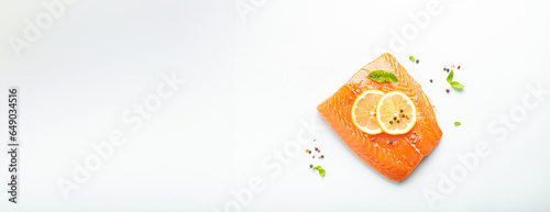 Fresh raw salmon marbled fillet isolated on white background with lemon, coarse salt, green herbs top view. Healthy nutrition and balanced diet. Copy space