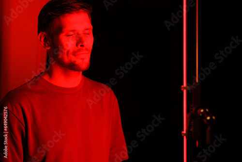 Embarking on red light therapy, the gentleman faces the camera in a portrait at a beauty salon, utilizing a red light device as a component of his anti-aging cosmetic treatment