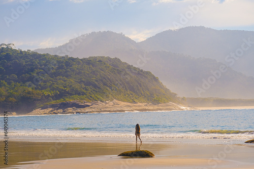 Young girl walks along the beach along the sea. Big island Ilha Grande aventureiro beach Angra dos Reis, Rio de Janeiro, Brazil photo