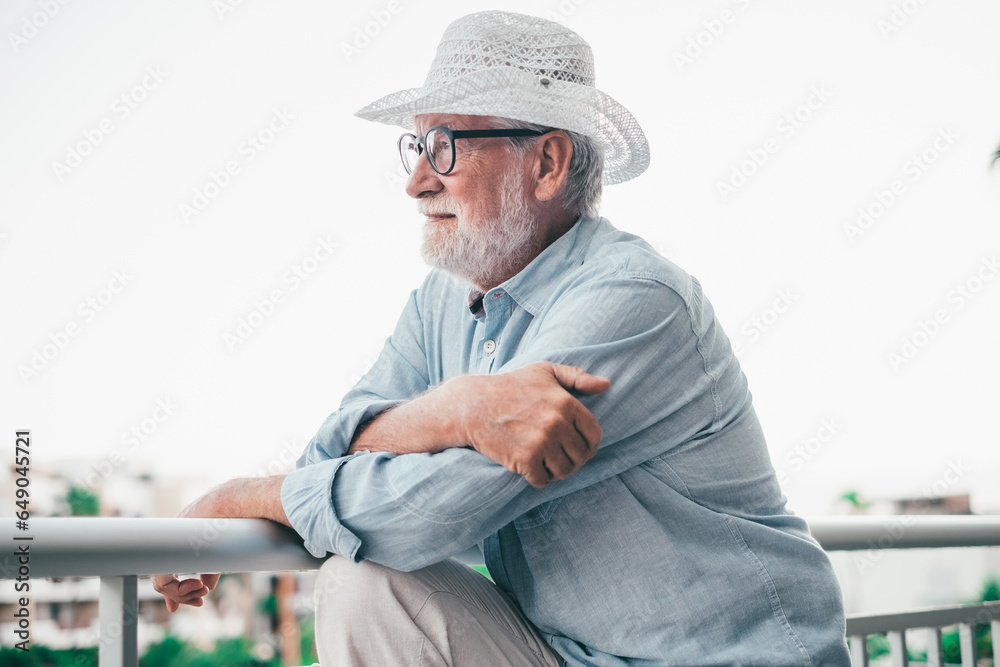 Side view of handsome relaxed smiling senior man leaning on balcony railing looking away Side view of handsome relaxed smiling senior man leaning on balcony railing looking away