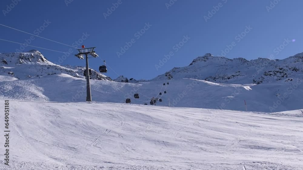 Empty ski slope in Hochgurgl ski resort on beautiful sunny day with moving gondola ski lifts, located in the Austrian alps. Empty ski slope in Hochgurgl ski resort on beautiful sunny day with moving gondola ski lifts, located in the Austrian alps.