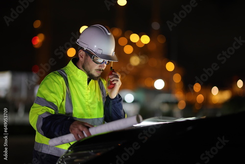 Portrait smart engineer with a safety green jacket and white hard hat working at night